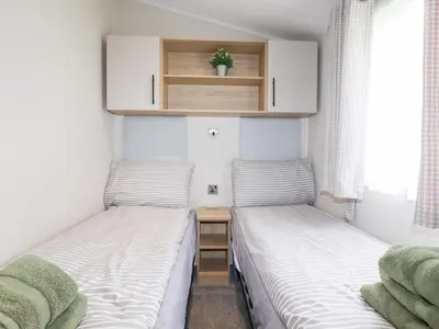 two beds in a small room with a small table at Meadow 46 in Newquay