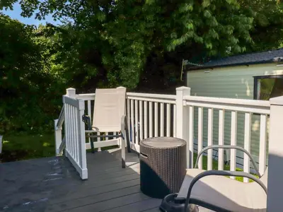 two chairs and a trash can on a deck at Meadow 46 in Newquay