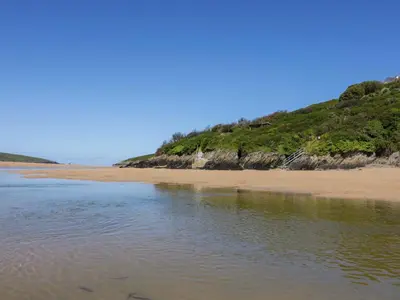 a sandy beach with a hill in the background at Meadow 46 in Newquay