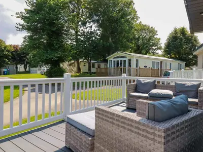 a patio with a white fence and a couch at Meadow 46 in Newquay