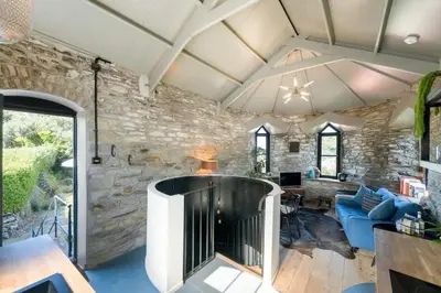 a living room with a stone wall at Castle by the Beach with Sea Views Portreath in Redruth