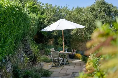 a patio with a table and an umbrella at Castle by the Beach with Sea Views Portreath in Redruth