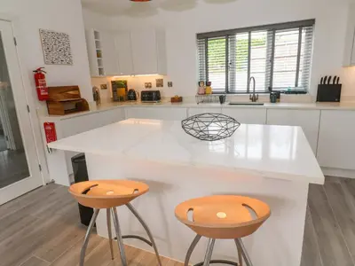 a kitchen with a white counter and two stools at Miramar in St Ives