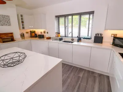 a white kitchen with white cabinets and a sink at Miramar in St Ives