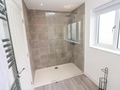 a walk in shower in a bathroom with a window at Miramar in St Ives