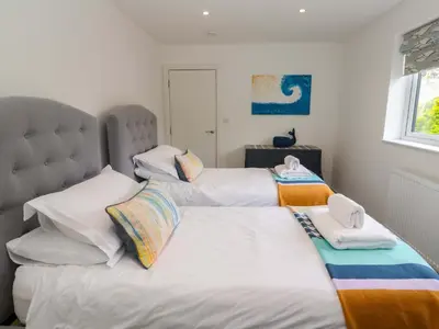 two beds in a bedroom with white sheets at Miramar in St Ives