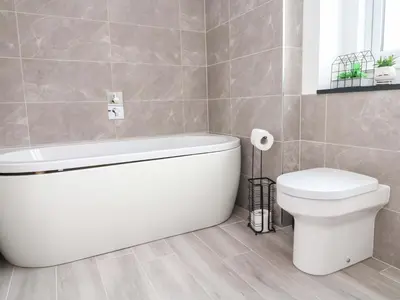 a bathroom with a white tub and a toilet at Miramar in St Ives