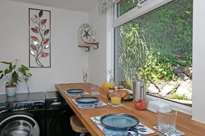 a kitchen with a table and a washing machine at 7 Porth Valley Cottage's in Newquay