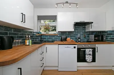 a kitchen with white cabinets and blue subway tiles at 7 Porth Valley Cottage's in Newquay