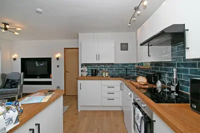 a kitchen with white cabinets and a counter top at 7 Porth Valley Cottage's in Newquay