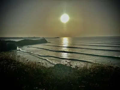 a sun setting over the ocean with a beach at 7 Porth Valley Cottage's in Newquay