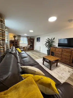 a living room with a leather couch and a television at Adorable 3 Bedroom House, Near Newquay 11 Miles in Saint Dennis