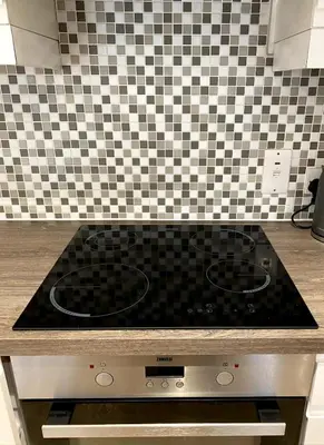 a stove top in a kitchen with a tiled wall at Lovely 1 bedroom flat in the heart of Newquay in Newquay