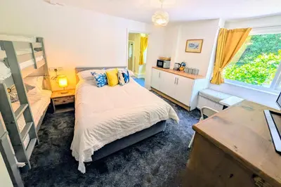a bedroom with a bed and a desk and a window at Parkside Lodge Manor in Camelford