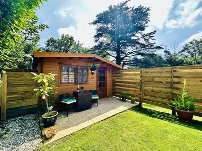 a small cabin with a table and chairs in a yard at Harvey's Lodge in Helston