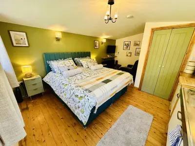 a bedroom with a bed with a blue headboard at Harvey's Lodge in Helston