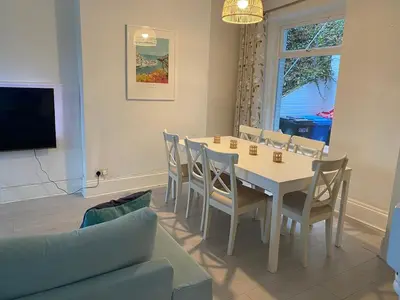 a dining room with a table and chairs and a couch at Cornwall Large Beach House Sea & Beach Views - 4 Bedrooms & 3 Bathrooms in Looe