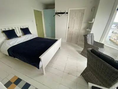 a bedroom with a bed and two chairs and a window at Cornwall Large Beach House Sea & Beach Views - 4 Bedrooms & 3 Bathrooms in Looe