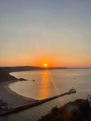 a sunset over a beach with a boat in the water at Cornwall Large Beach House Sea & Beach Views - 4 Bedrooms & 3 Bathrooms in Looe