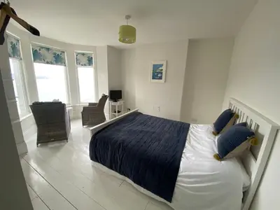 a bedroom with a large bed with blue pillows at Cornwall Large Beach House Sea & Beach Views - 4 Bedrooms & 3 Bathrooms in Looe