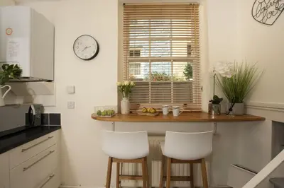 a kitchen with a counter with two white stools at Bessie Ellens Cottage - 1 Pet Welcome - Central Location - Free WiFi in Fowey