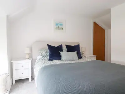 a bedroom with a large bed with blue pillows at Glendale in Port Isaac