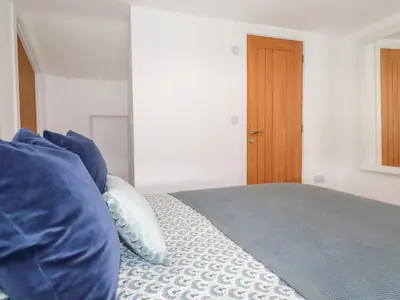 a bedroom with a bed with blue pillows and a wooden door at Glendale in Port Isaac
