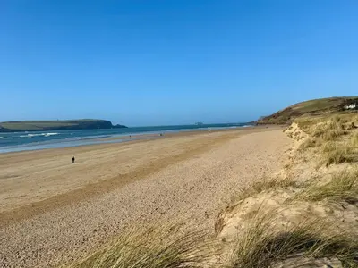 a sandy beach with people walking on the water at Glendale in Port Isaac