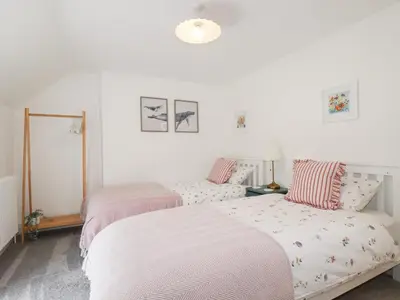 two beds in a bedroom with white walls at Glendale in Port Isaac