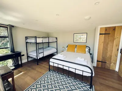 a bedroom with two bunk beds and a piano at Luxury Cornish Cottage & Modern Cabin with Garden, Central St Agnes in St. Agnes