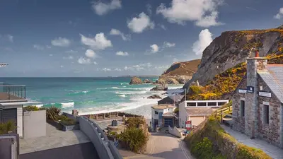 a view of a beach with a building and the ocean at Luxury Cornish Cottage & Modern Cabin with Garden, Central St Agnes in St. Agnes