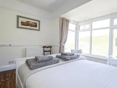 a bedroom with a white bed with two pillows on it at Sea Ledge in Tintagel