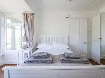 a white bedroom with a white bed with towels on it at Sea Ledge in Tintagel