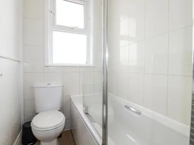 a white bathroom with a toilet and a window at Sea Ledge in Tintagel