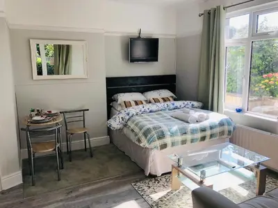 a bedroom with a bed and a table and a tv at The Studio in St Austell