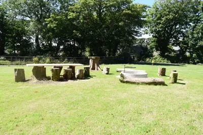 a park with a picnic table and logs in the grass at La Casita in Breage