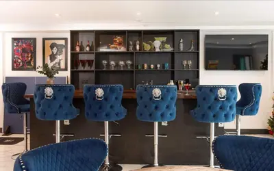 a bar with blue chairs in a room at La Casita in Breage