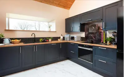 a kitchen with navy blue cabinets and a window at La Casita in Breage