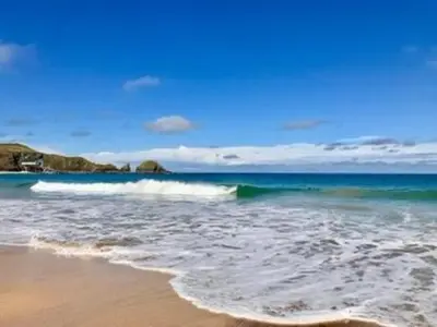 a wave in the ocean on a sandy beach at Seabreeze Cottage in Padstow