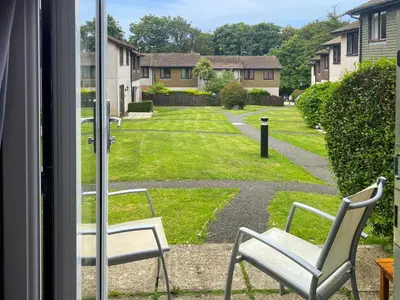 two chairs sitting in a window looking out at a yard at Strawberry Hill in Hayle