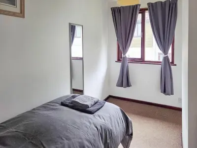 a bedroom with a bed and two windows at Strawberry Hill in Hayle