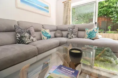 a living room with a couch and a glass table at Jaluna in St Ives