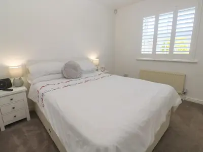 a bedroom with a large white bed and a window at Jaluna in St Ives