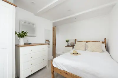 a bedroom with a white bed and a dresser at Charming Cottage by the Sea, Wi-Fi, Pets in St Ives