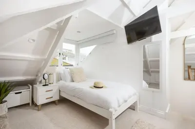a white bedroom with a bed and a tv at Charming Cottage by the Sea, Wi-Fi, Pets in St Ives