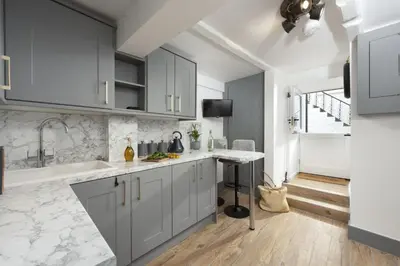 a kitchen with white cabinets and marble counter tops at Charming Cottage by the Sea, Wi-Fi, Pets in St Ives