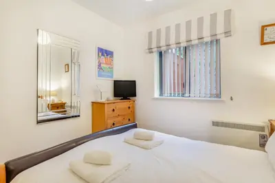 a white bedroom with a bed and a television at 2 Bed in Fowey oc-s25324 in Fowey