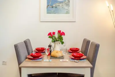 a table with red dishes and a vase with flowers at 2 Bed in Fowey oc-s25324 in Fowey