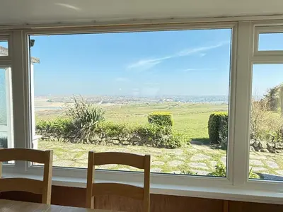 a window with two chairs and a view of a field at 2 The Links in St Ives