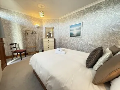 a bedroom with a large white bed and a chair at 2 The Links in St Ives